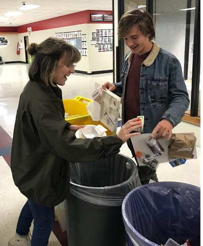 Junior Louis Caerts, a student from Belgium and a Beta Chi Pi member, helps senior Kate Terreri learn what to throw away and what to compost. 