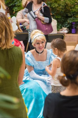 Mikel, dressed as Cinderella, smiles as she listens to a little girl.