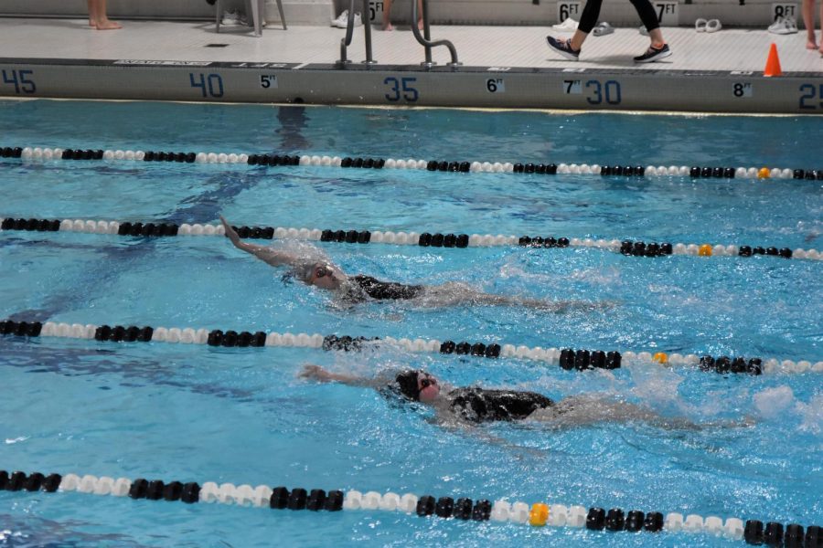 Junior Kylee Sullivan and sophomore Carly Shaffer swim a backstroke relay in a meet from last year.