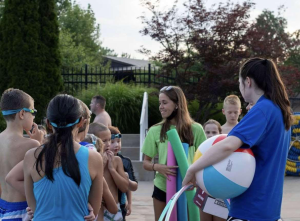 Junior Alison Stark talks to a group of kids before starting swim lessons at Manchester Acquatic Center.