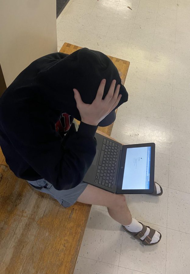 Senior Sam Taylor shows his frustration when his math assignment wont load in the gym hallway.
