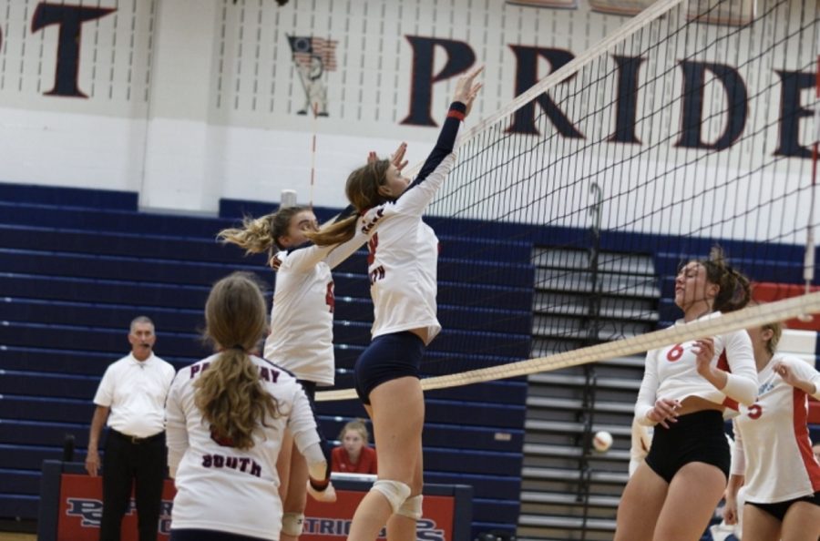 No. 8, freshman Elisabeth Uschold, leaps up in the air to block the shot of her opponent during a volleyball game. Photo by Manxiang Fu.