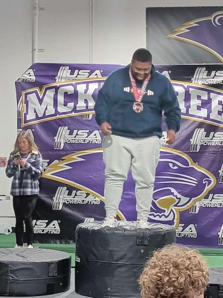 Senior Myles Mobley stands on the podium after receiving a gold medal for a powerlifting competition at McKendree University.
