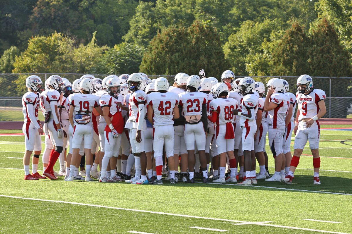 The Patriot varsity football team gets together for a huddle before a game last season. 