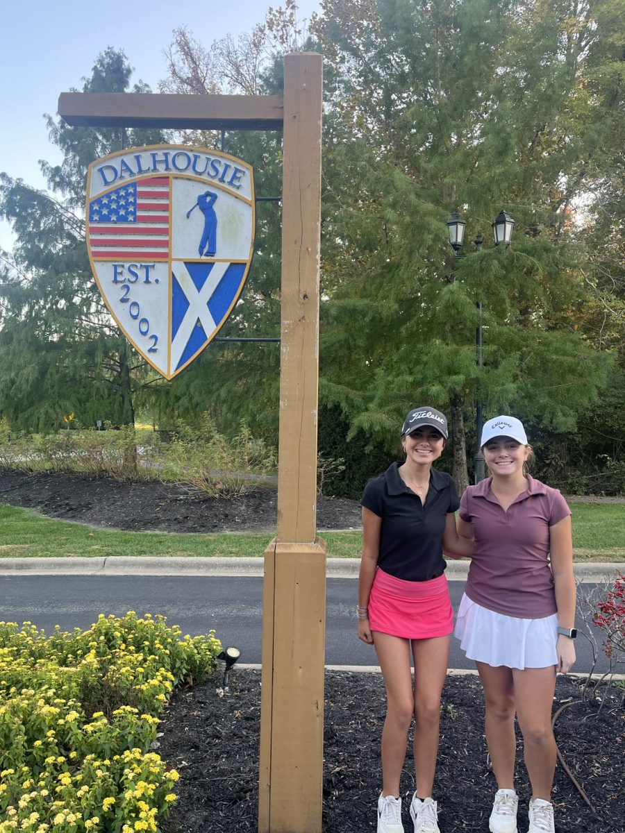 Ashtynn Zuniga and Audrey Miller take a picture next to the Dalhousie Country Club sign before the state tournament began.