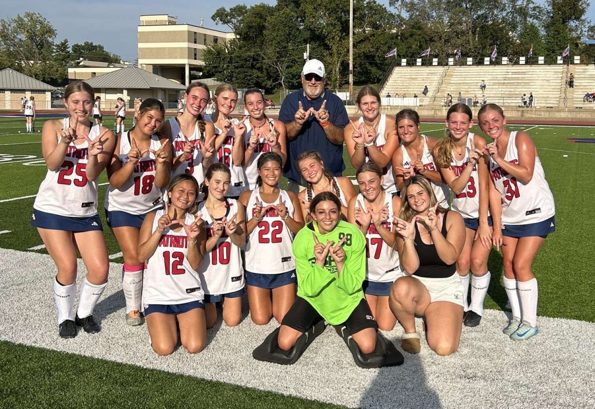 The varsity girls field hockey team gathers around Coach Dave Richardson after he achieved his 100th win. 