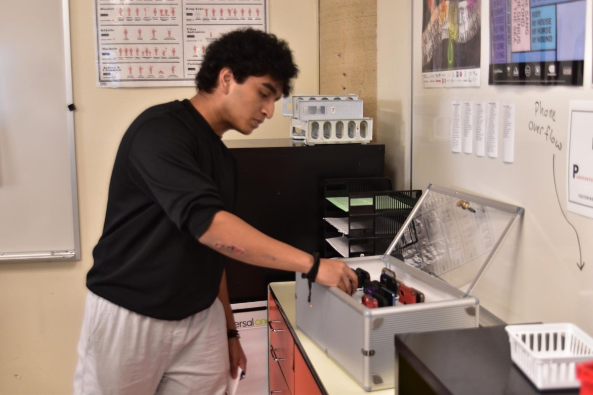 Senior Farhan Gulzar puts his cell phone into the phone locker before class starts in Mr. Wissinger's room. 