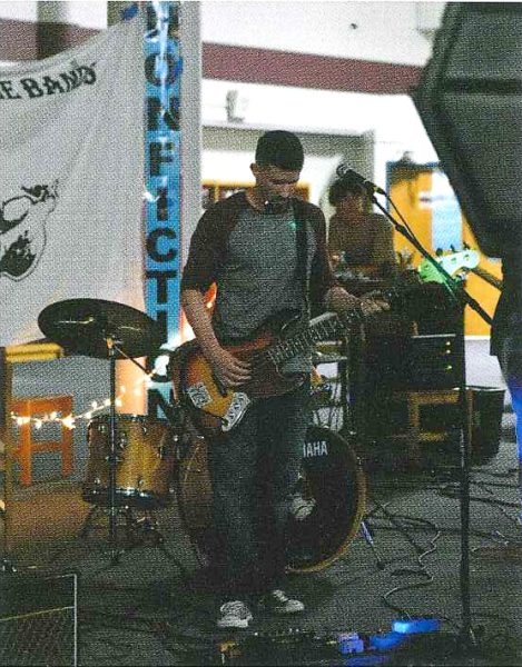 In a picture scanned from the 2019 yearbook, social studies teacher Jim Lake rocks out on his bass during the last Battle of the Bands, held in the library.