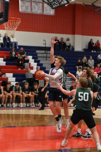 Senior guard Noah Barnes switches hands mid-air as he drives to the basket in the Patriots' pre-season home opener.