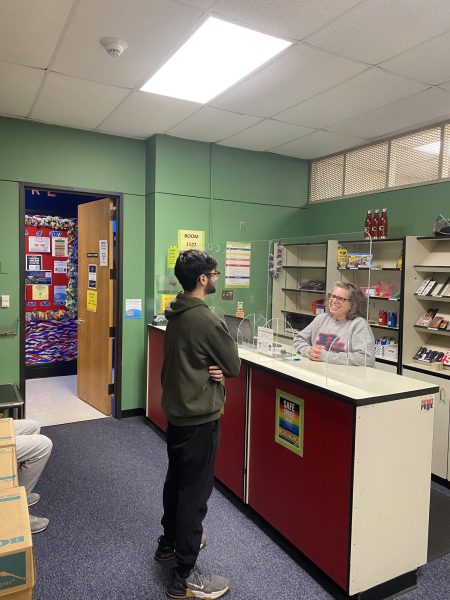 Senior Yahya Sadiq talks with Mary Robinson at the school store to find out if he has to pay any fines or fees.