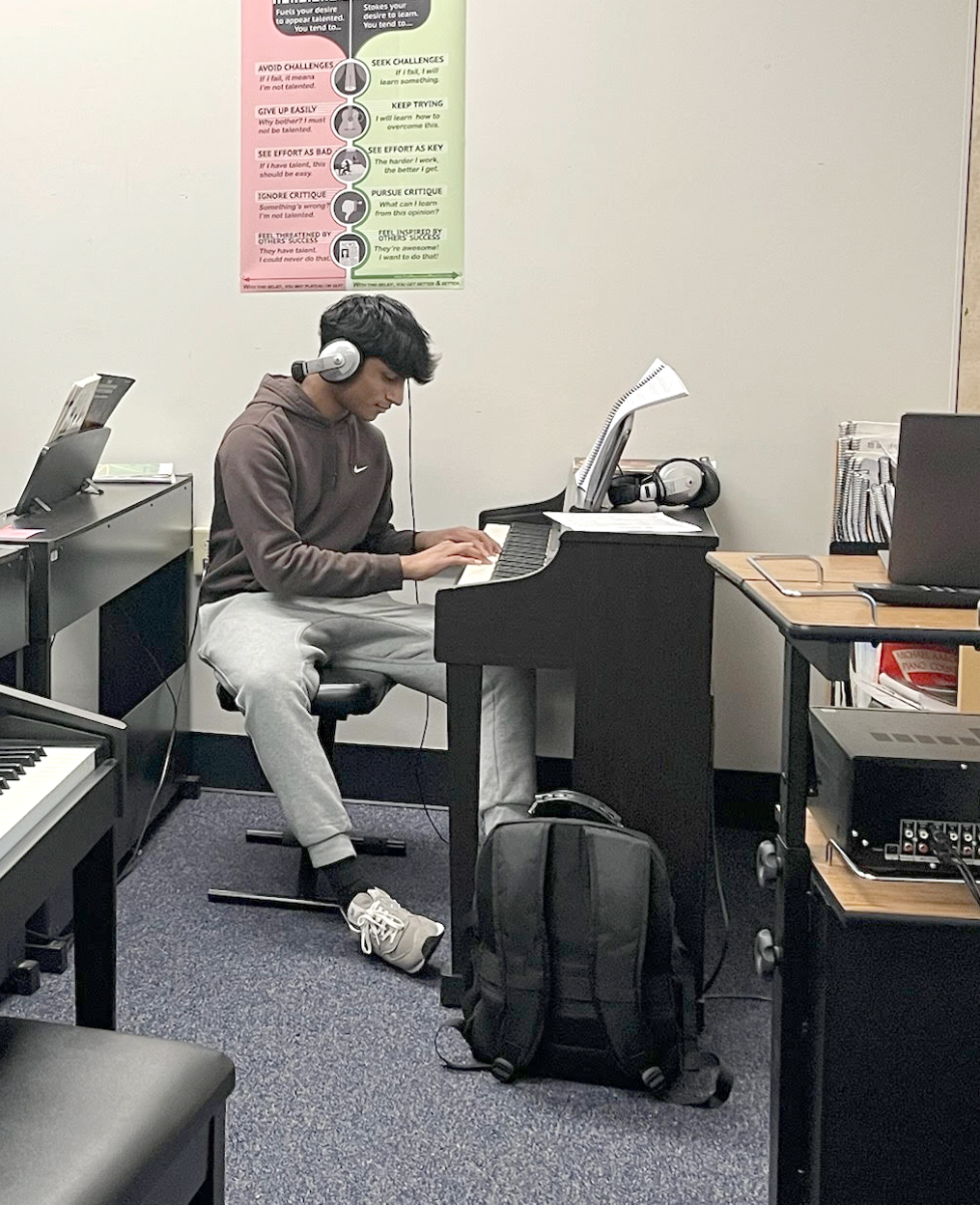 With his headphones on to hear the music, freshman Adi Senthilnathan practices during Piano class. 