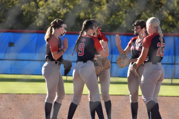 Pitcher Maddie Sherry high fives first baseman Elle Haston before the softball game starts. 