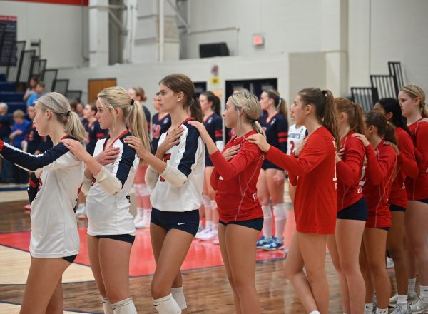 Nine freshmen volleyball players stand for the National Anthem before the varsity game against Fox.