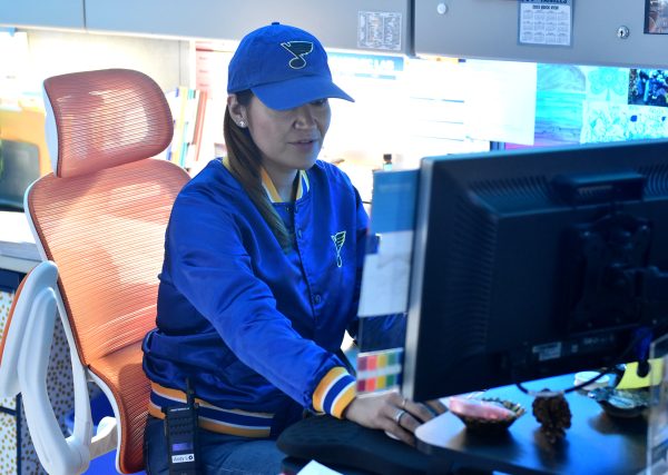 Decked out in her Blues hat and jacket, administrative assistant Andy Lane works at her desk. 