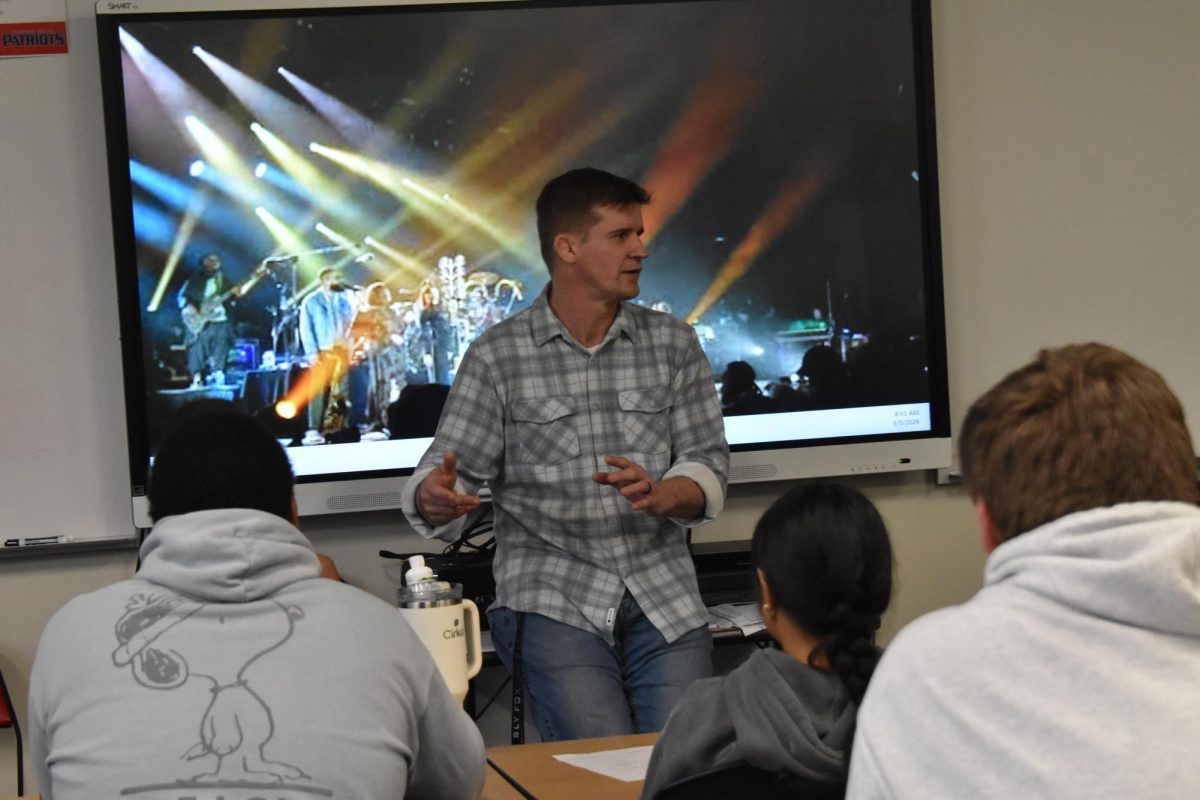 With a concert playing in the background, social studies teacher Jim Lake talks to his History Through Music class. Lake also teaches Modern Warfare.