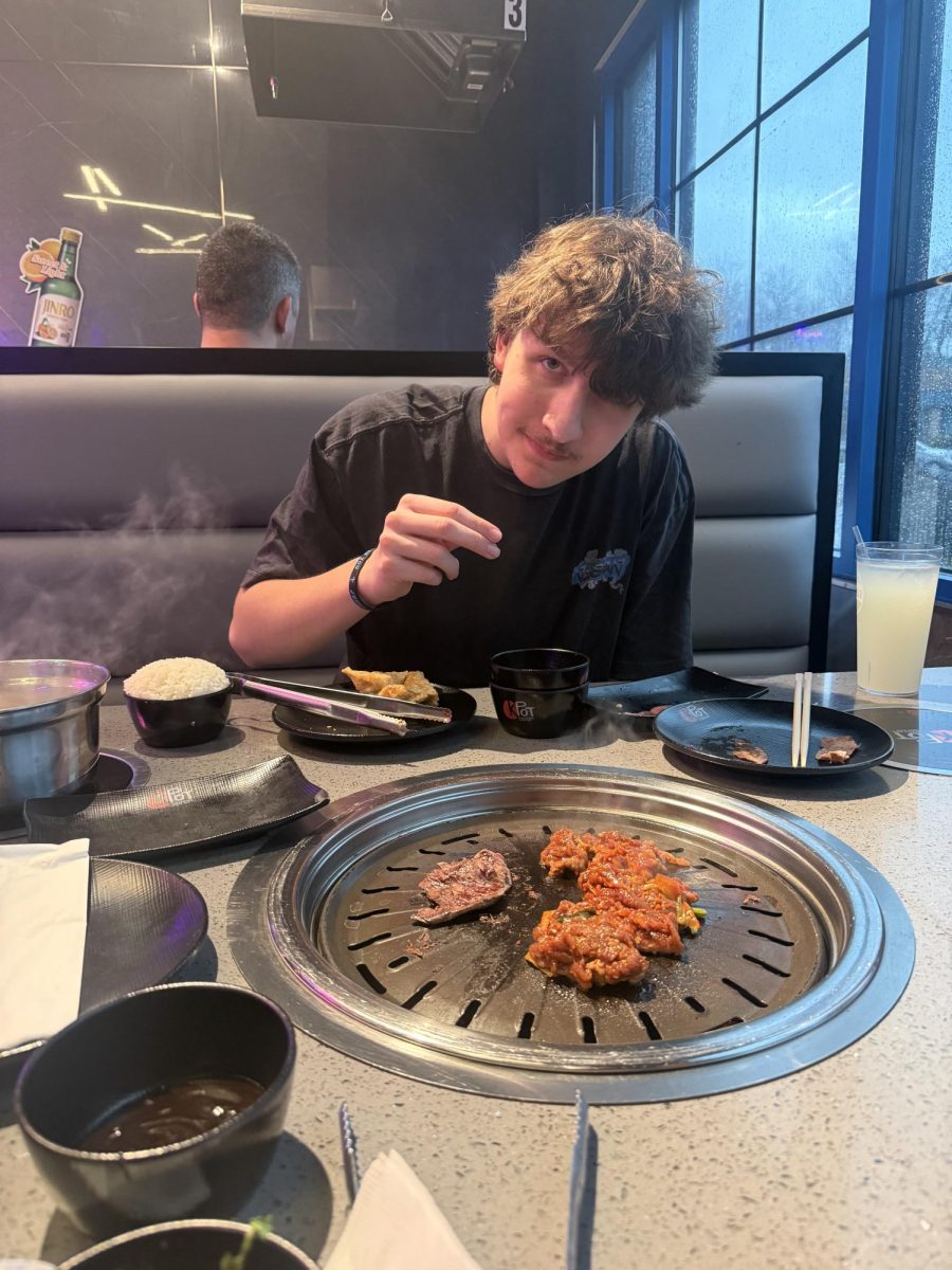 Junior Isaac Wyrich takes a photo while trying some samosas at KPOT Korean BBQ & Hot Pot on Manchester.