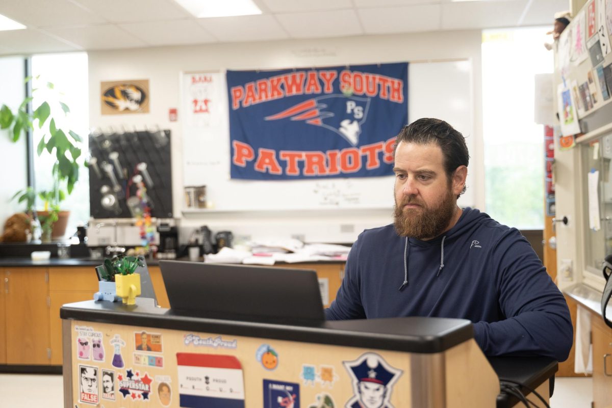 With a Patriot flag behind him on his wall, science teacher Brad Zerman works on grading, April 27. Along with teaching, Zerman coaches the throwers on the Patriot boys track team.