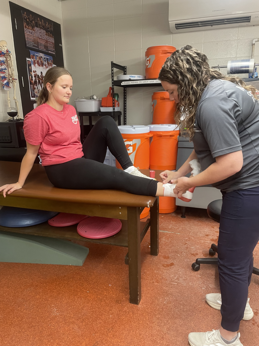 Freshman Ady Clinard gets her ankle wrapped by trainer Abby Pryor after track practice. Clinard was having pain while running.